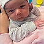 William joined the competition — help win amazing prizes! baby, infant, hat, striped_clothing, pink_sweater, hand, face, eyes, curious, indoor, person, child, newborn, soft_lighting, blurred_background, headwear, cute, skin, portrait, holding