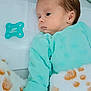 baby, infant, pacifier, blanket, mint_green, onesie, sleepwear, soft_texture, hand, face, lying_down, comfort, cozy, newborn, cute, peaceful, resting, indoor, child, portrait
