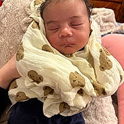 Ousman participe au concours pour gagner de l'argent avec cette photo : baby, sleeping, blanket, teddy_bear_pattern, soft_texture, curly_hair, infant, wrapped, cozy, indoor, person, peaceful, resting, cute, child, portrait, comfort, warm, furniture, home
