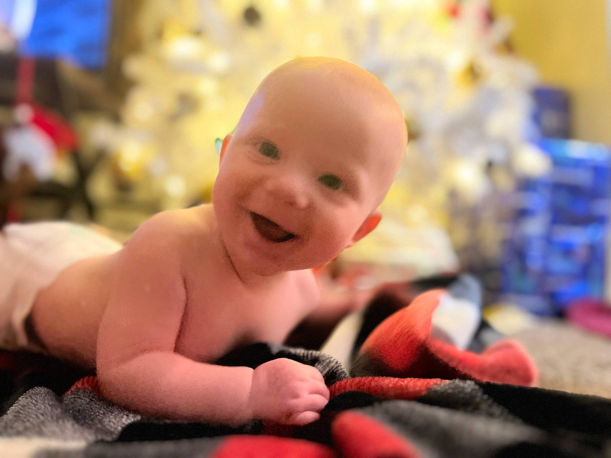 Noah is registered to the contest to win money with this photo: baby, baby_laughing, baby_toddler_clothing, carmine, cheek, child, christmas_tree, comfort, event, fun, happy, holiday, laugh, person, play, room, sitting, skin, smile, thumb