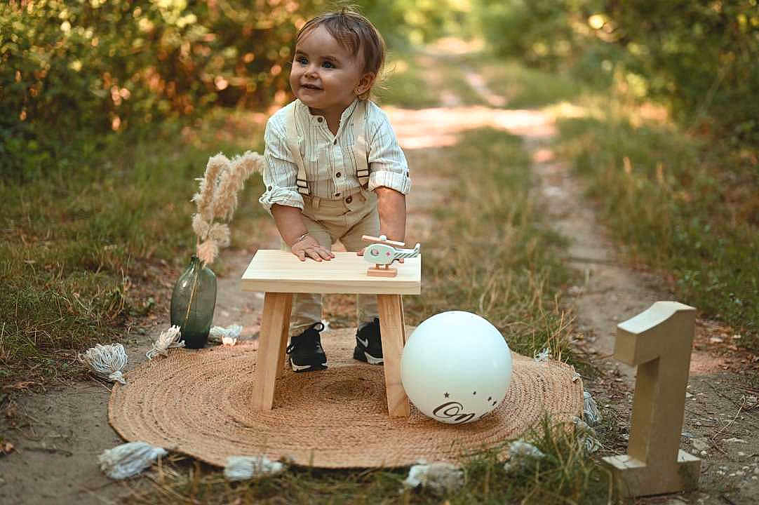 Lorys a rejoint le concours — aidez-le/la à gagner de superbes lots ! toddler, child, outdoor, nature, grass, balloon, wooden_stool, number_one, decor, vase, pampas_grass, pathway, smiling, suspenders, shoes, round_mat, celebration, portrait, happy, daylight