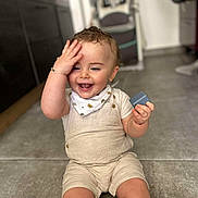 Lorys a rejoint le concours — aidez-le/la à gagner de superbes lots ! toddler, child, smiling, happy, indoor, floor, block, hand, face, clothing, shorts, bib, bracelet, kitchen, cabinet, tile_floor, person, sitting, play, cute