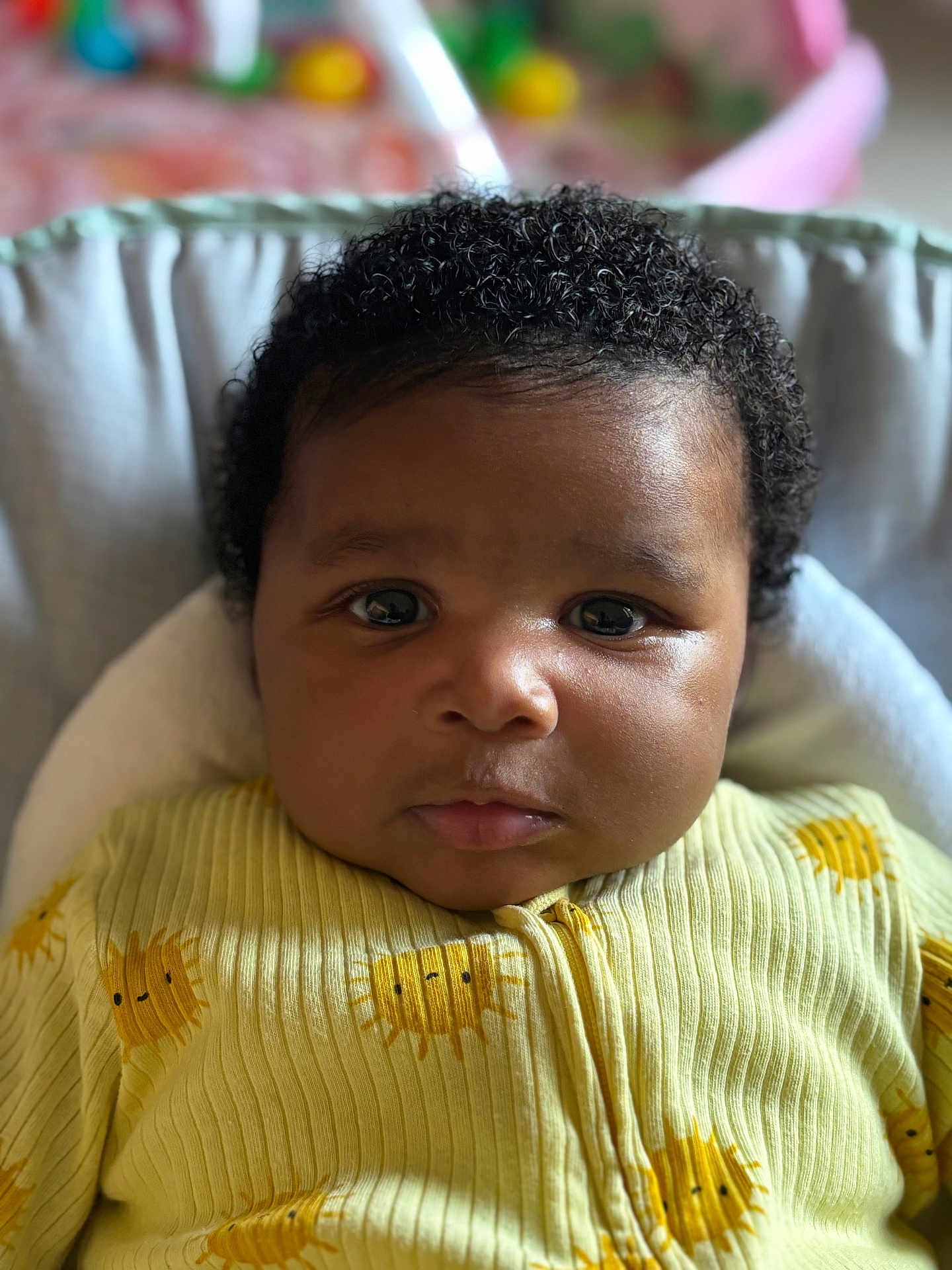 Nahée a rejoint le concours — aidez-le/la à gagner de superbes lots ! baby, child, portrait, curly_hair, yellow_clothing, sun_pattern, close_up, face, infant, cute, indoors, soft_background, young_child, cozy, expression, person, sitting, apparel, newborn, head