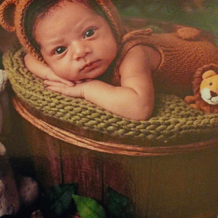 Emekai joined the competition — help win amazing prizes! baby, infant, knitted_clothing, bear_costume, basket, green_cushion, leaves, sticks, wooden_floor, portrait, cute, resting, indoors, baby_face, costume, soft_lighting, child, newborn, expression, props