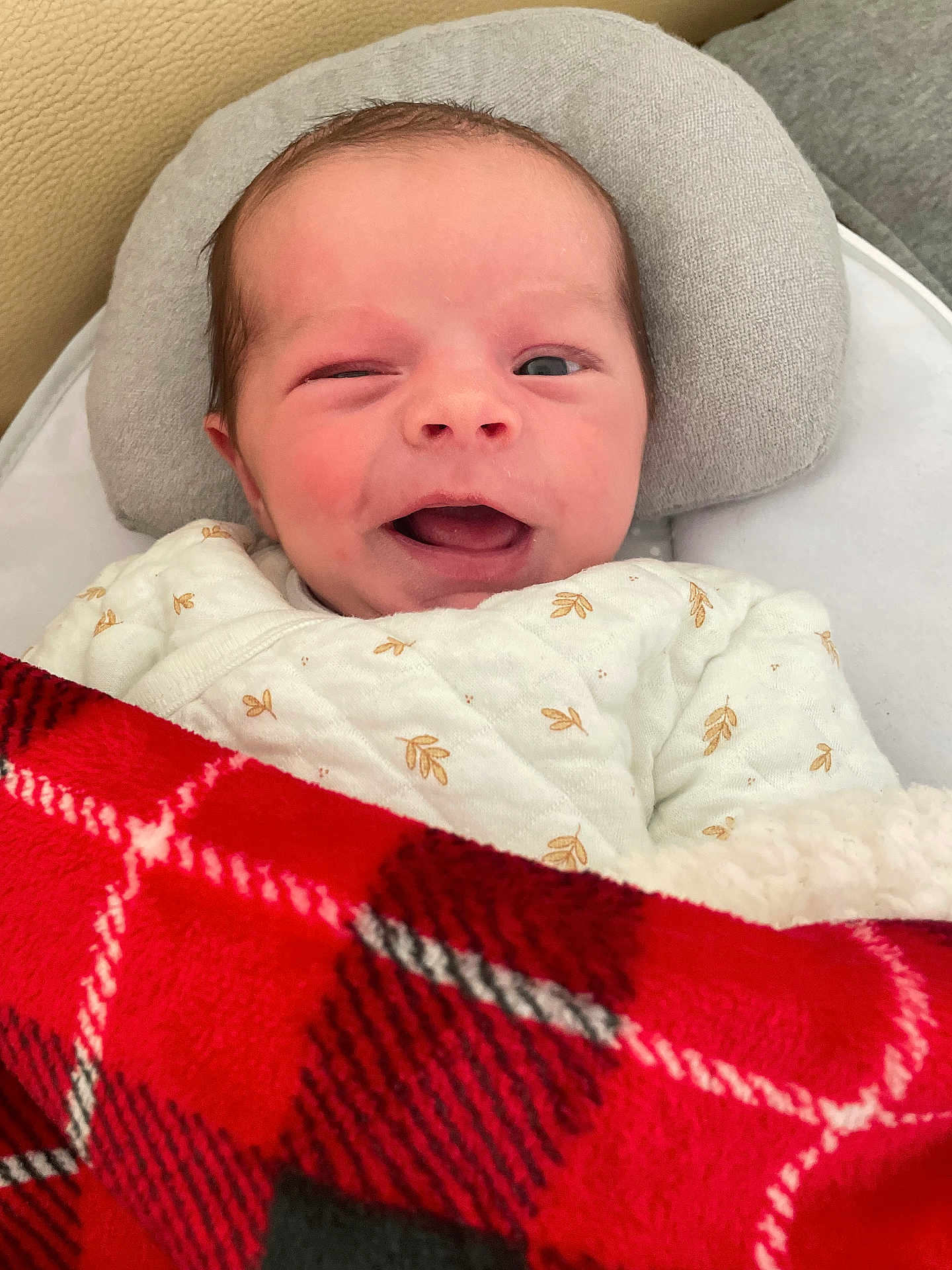 élio participe au concours pour gagner de l'argent avec cette photo : baby, newborn, infant, winking, smiling, blanket, red_blanket, plaid, pillow, cozy, white_outfit, cute, face, head, person, resting, indoors, soft, comfort, child
