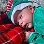 élio participe au concours pour gagner de l'argent avec cette photo : baby, blanket, christmas, closeup, cozy, cute, face, festive, green_clothing, hand, hat, holiday, indoors, infant, plaid, portrait, red_clothing, sleepy, soft_light, tinsel
