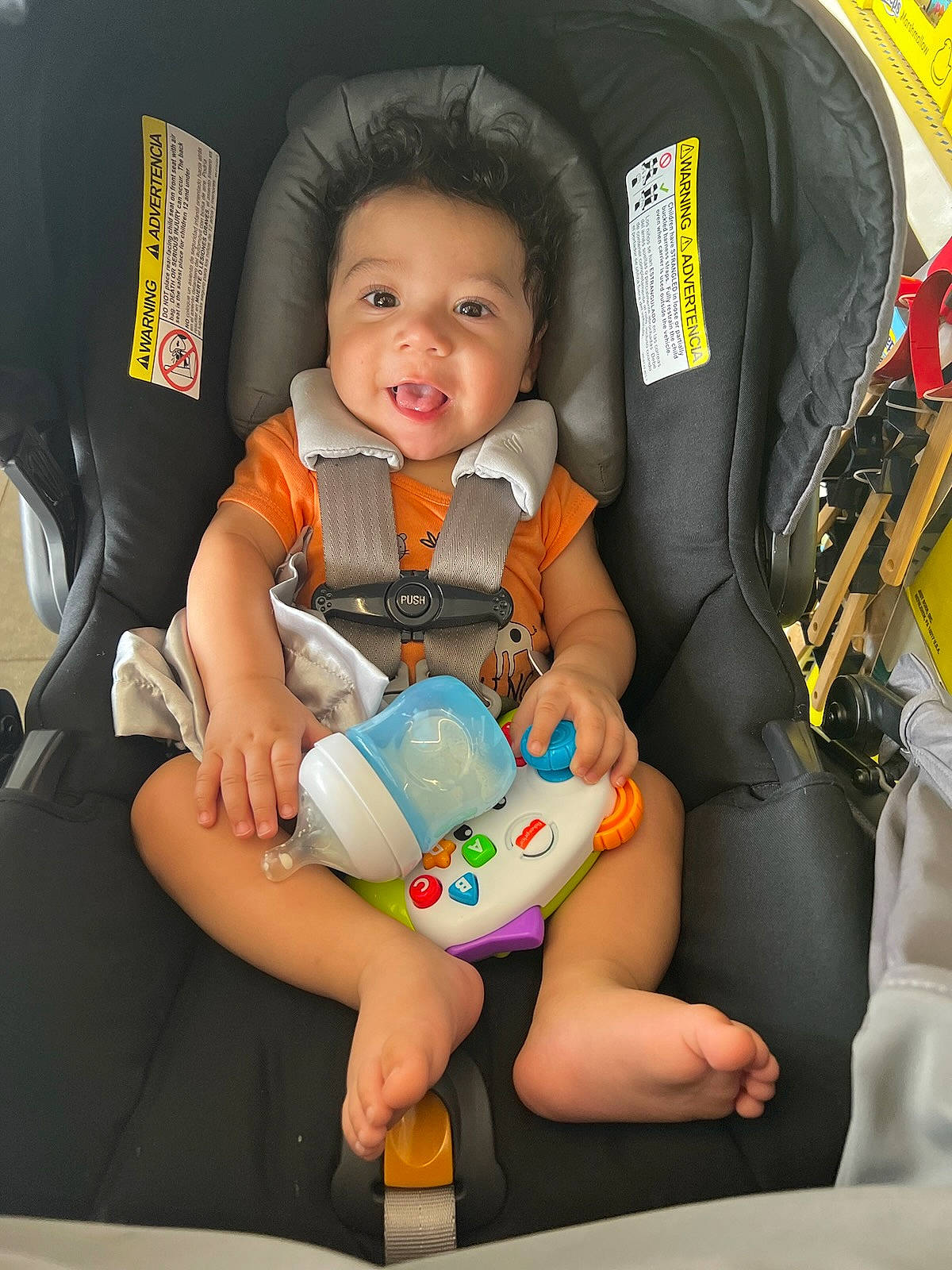 Josue is registered to the contest to win money with this photo: arm, auto_part, baby, baby_in_car_seat, baby_products, baby_toddler_clothing, car_seat, child, comfort, fun, hand, happy, lap, person, product, seat_belt, sitting, sleeve, smile, toddler