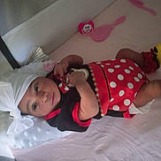 Al'Sheerah is registered to the contest to win money with this photo: baby, infant, playpen, headwrap, yellow_shoes, polka_dot_dress, pacifier, baby_brush, pink, red, black, white, lying_down, cute, child, soft_surface, indoors, young, wearing_clothes, baby_accessories