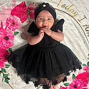 Selena joined the competition — help win amazing prizes! baby, black_dress, headband, flower, blanket, floral_pattern, pink_flowers, red_flowers, infant, cute, happy, lying_down, hands, feet, soft_texture, portrait, child, adorable, smiling, indoor