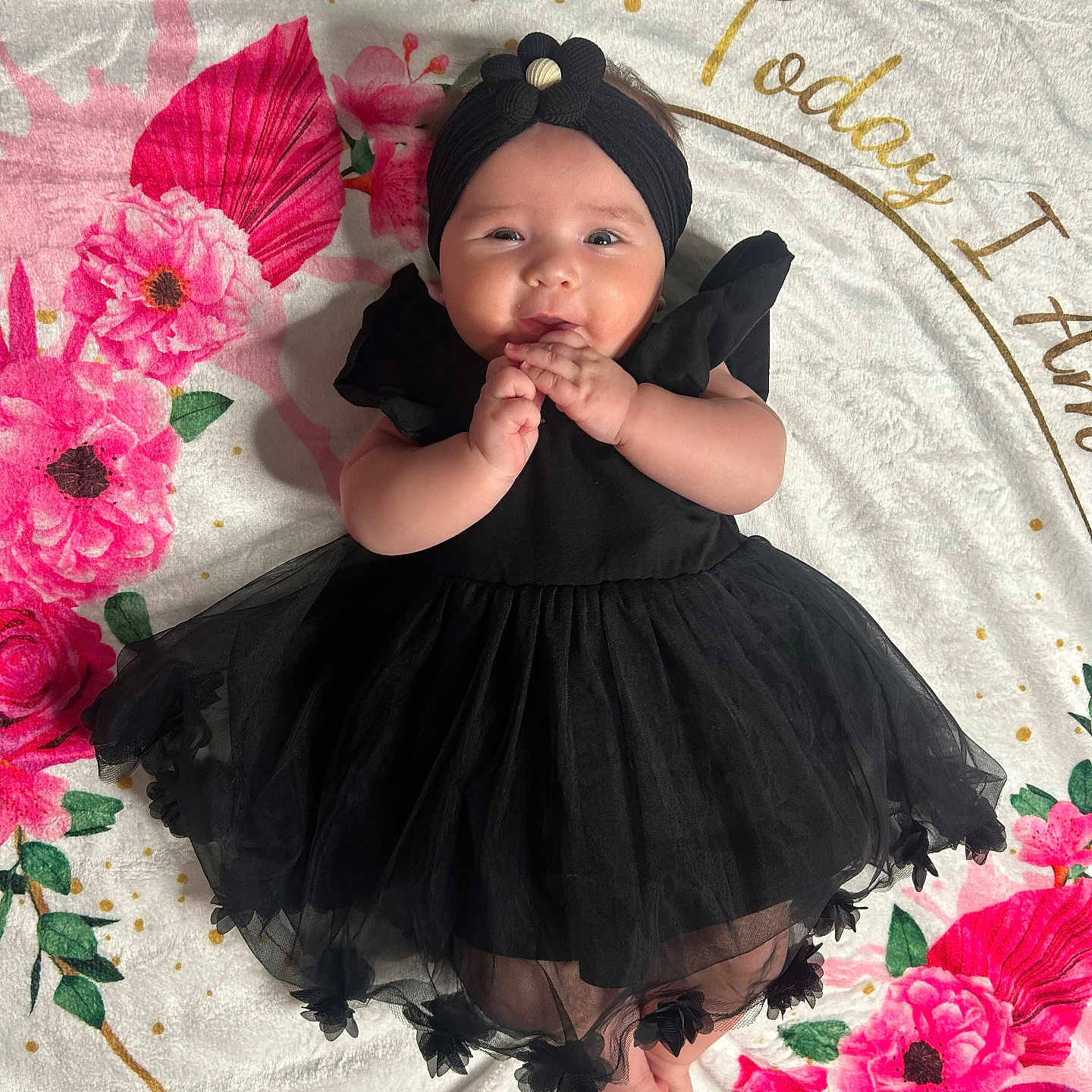 Selena joined the competition — help win amazing prizes! adorable, baby, black_dress, blanket, child, cute, feet, floral_pattern, flower, hands, happy, headband, indoor, infant, lying_down, pink_flowers, portrait, red_flowers, smiling, soft_texture