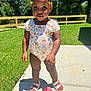toddler, child, outdoor, sunny, grass, sidewalk, fence, blue_sky, romper, sandals, sippy_cup, person, cute, smiling, summer, daylight, young_child, nature, portrait, standing