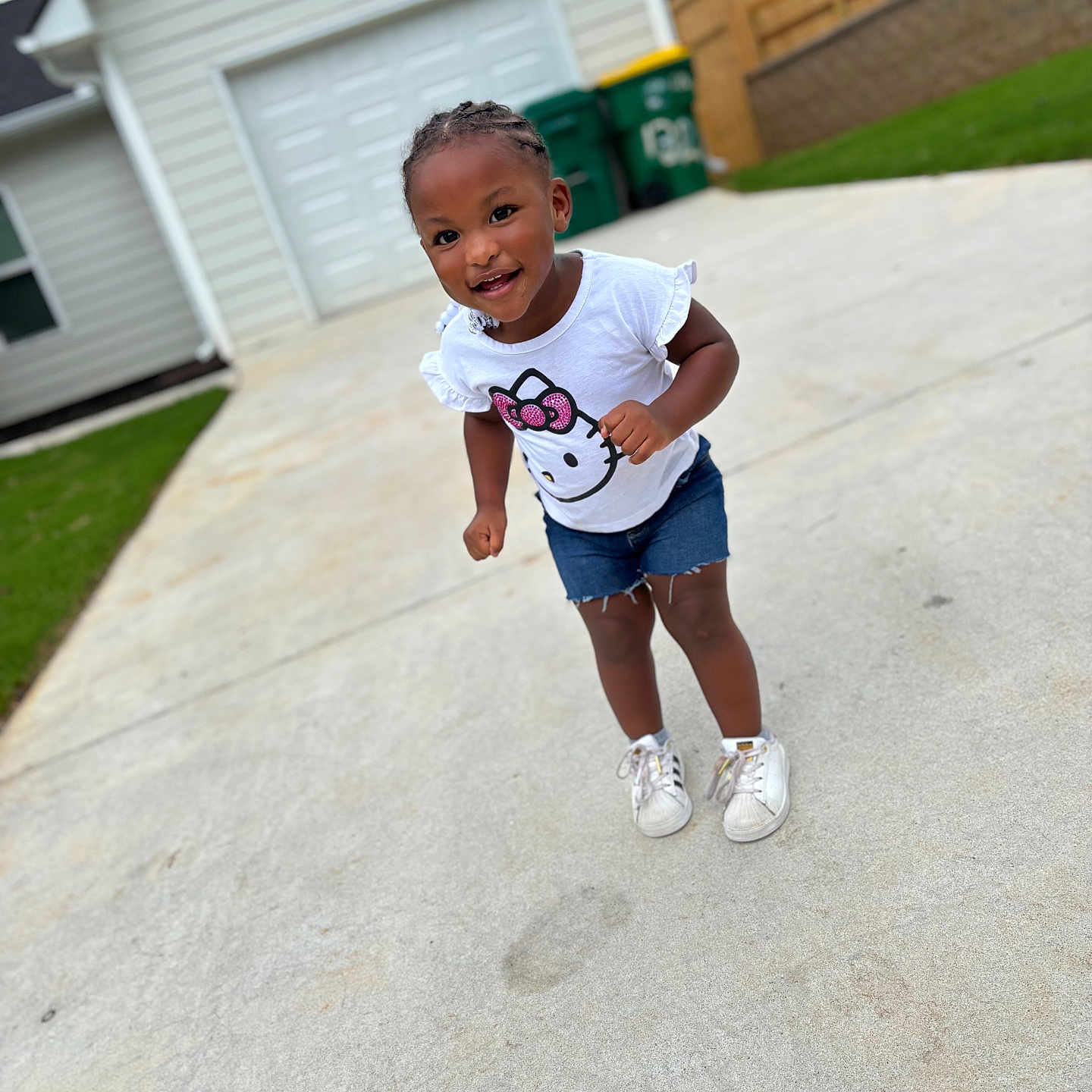 Kisaani joined the competition — help win amazing prizes! braided_hair, casual_clothing, child, concrete, daylight, denim_shorts, driveway, garage, green_trash_bins, happy, hello_kitty, house, outdoor, person, playful, smiling, suburban, toddler, white_sneakers, white_tshirt