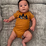 Colton is registered to the contest to win money with this photo: baby, infant, onesie, clothing, couch, furniture, face, person, child, cute, indoor, legs, arms, skin, head, expression, relaxed, lying, soft, comfortable