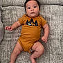 baby, infant, onesie, clothing, couch, furniture, face, person, child, cute, indoor, legs, arms, skin, head, expression, relaxed, lying, soft, comfortable