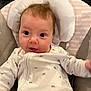 baby, infant, onesie, cushion, seat, face, red_hair, eyes, cute, smile, child, indoor, clothing, person, soft, comfort, baby_seat, expression, portrait, newborn