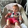 baby, infant, child, baby_rocker, toy, plush_toy, rattle, pink_shorts, minnie_mouse_shirt, shoes, footwear, couch, furniture, indoor, carpet, person, cute, seated, comfortable, home