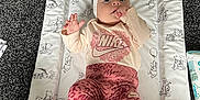 Darcie Rose is registered to the contest to win money with this photo: baby, infant, child, clothing, headband, carpet, changing_mat, nike, socks, hand, face, lying_down, pattern, toy, baby_product, floor, cute, indoors, soft, looking