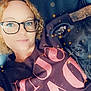 black_dog, casual_clothing, comfort, companion, curly_hair, dog, face, friendship, glasses, human, indoors, leather_couch, pet, portrait, relaxing, selfie, smile, sparkle_filter, tattoo, woman
