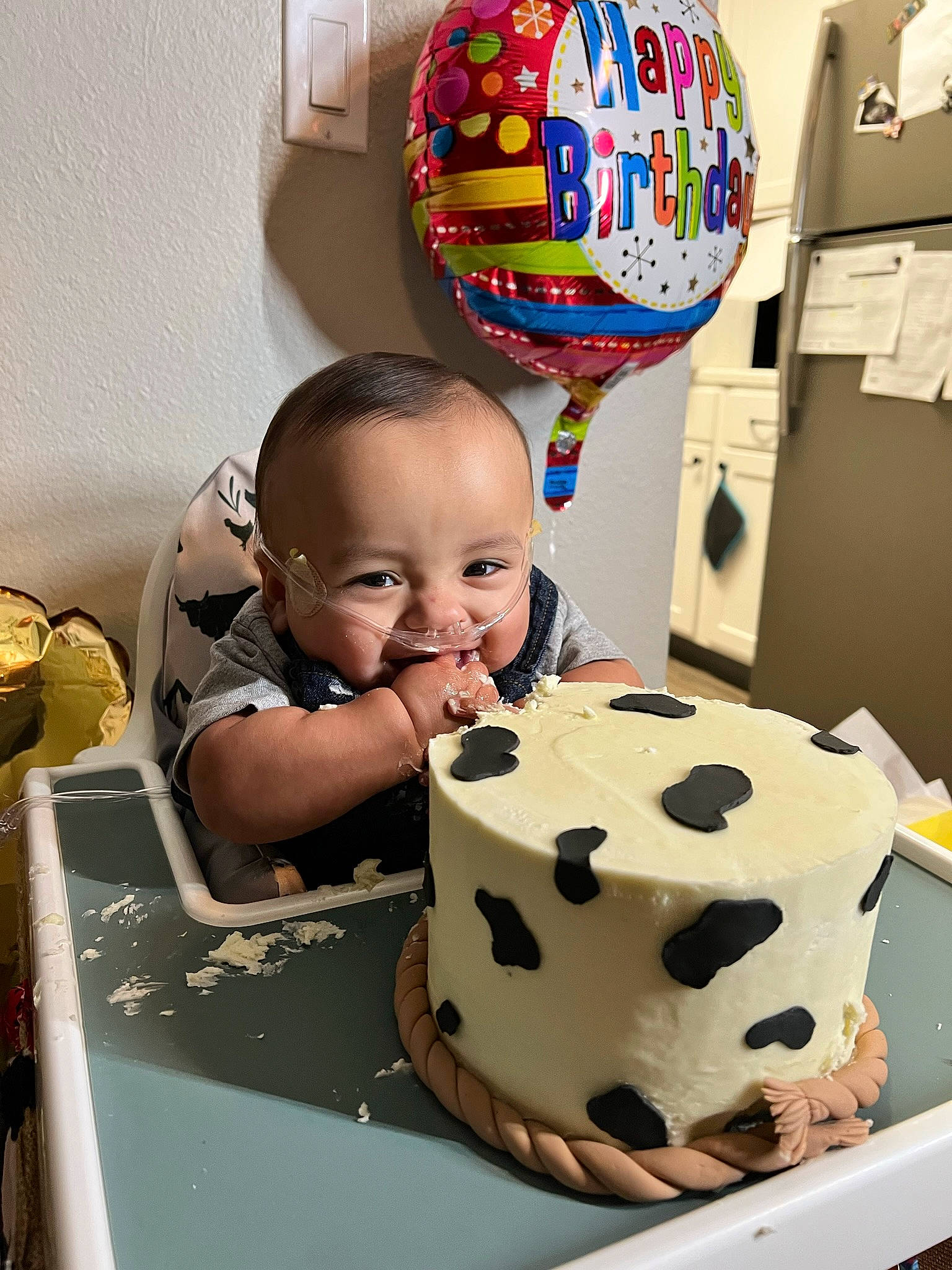 Kian is registered to the contest to win money with this photo: baked_goods, balloon, birthday, birthday_cake, buttercream, cake, cake_decorating, cake_decorating_supply, chair, food, happy, person, plate, shirt, smile, sugar_cake, sugar_paste, table, tableware, toddler