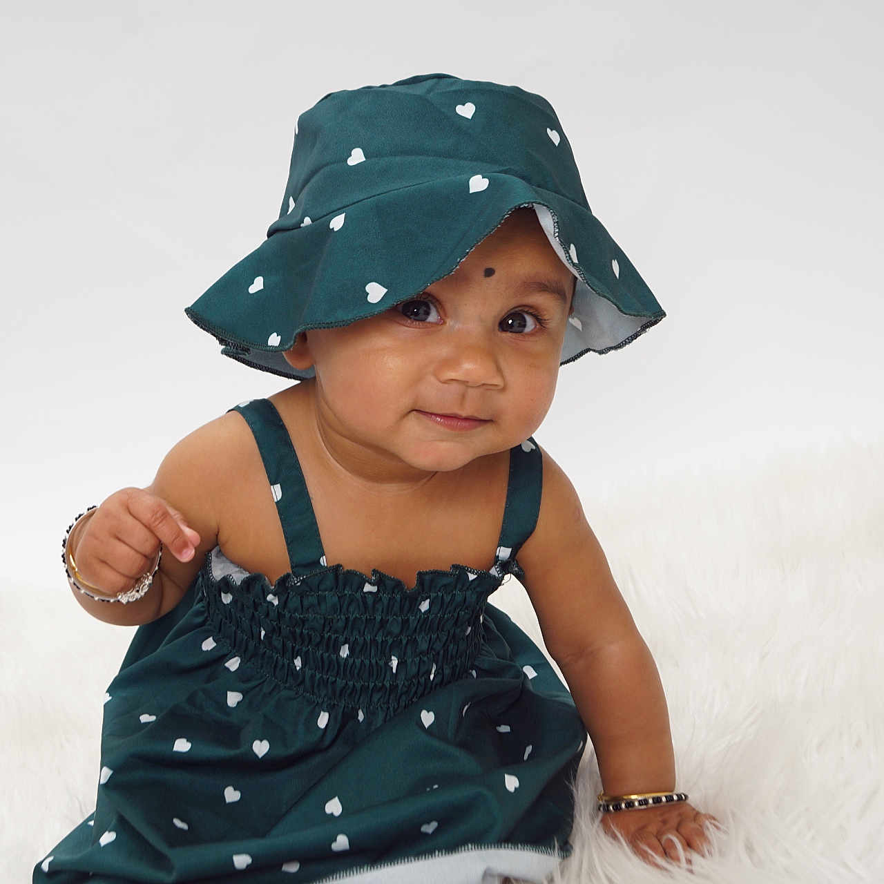 Kriti Animamalar is registered to the contest to win money with this photo: accessory, adorable, baby, bracelet, child, cute, dress, expression, face, fashion, fluffy_surface, girl, hat, infant, portrait, sitting, skin, smile, studio, white_hearts