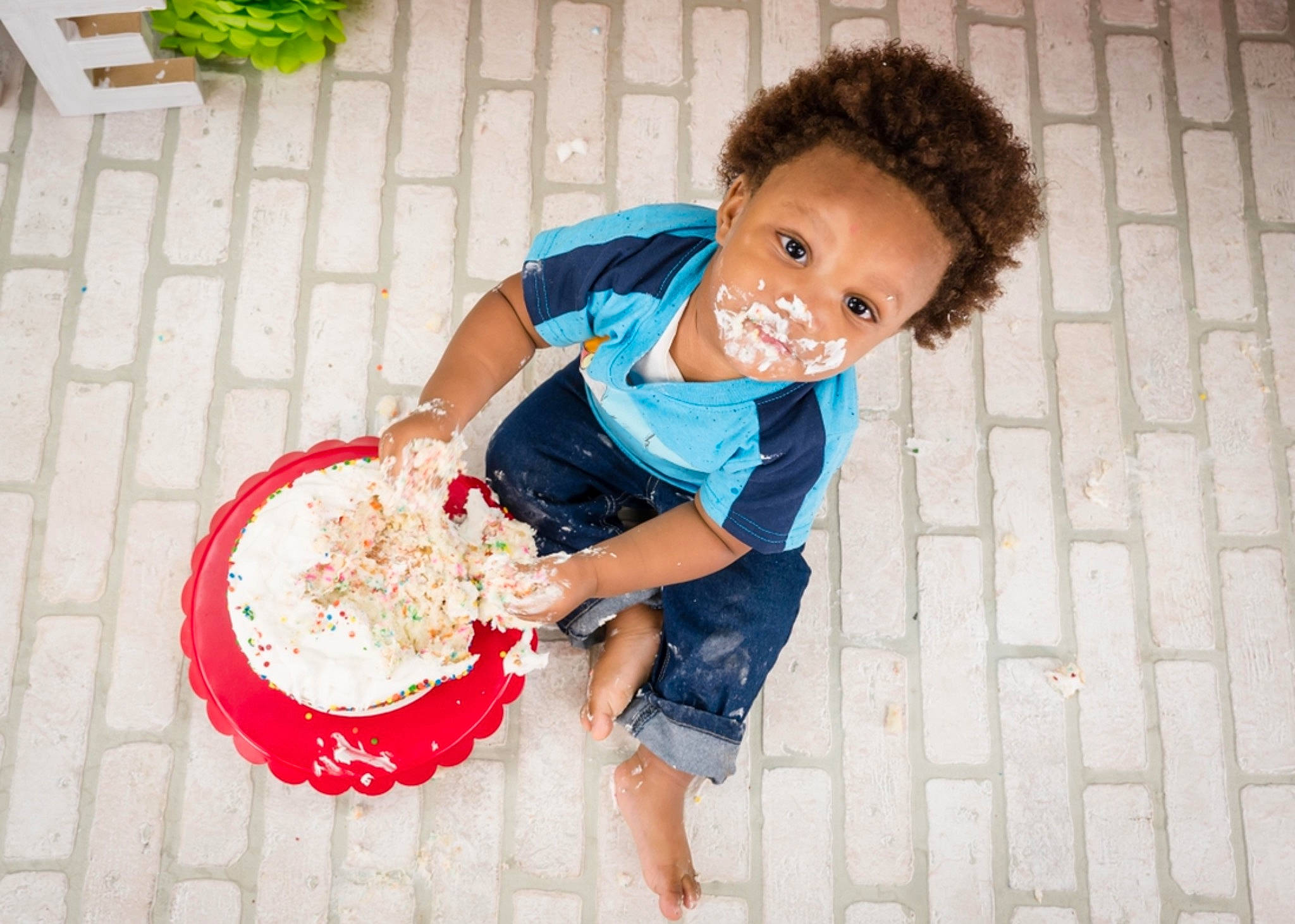 Kameron is registered to the contest to win money with this photo: afro, baby_toddler_clothing, child, circle, event, facial_expression, flooring, fun, happy, human, icing, leisure, pattern, person, play, sitting, sweetness, toddler