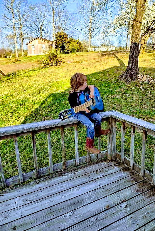 Gabe joined the competition — help win amazing prizes! electric_blue, fun, grass, green, handrail, landscape, leaf, leisure, luggage_and_bags, nature, people_in_nature, person, plant, recreation, sitting, sky, sneakers, sunlight, tree, wood