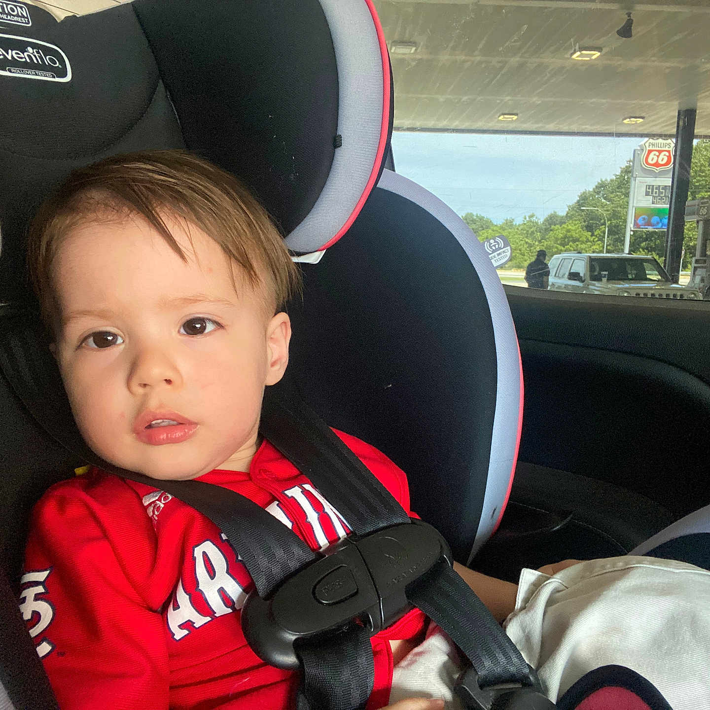 Ragna joined the competition — help win amazing prizes! toddler, child, car_seat, red_shirt, seatbelt, car_interior, window, gas_station, phillips_66, vehicle, safety, young_child, portrait, daylight, curious_expression, hair, face, person, seat, travel
