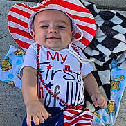 Valentino joined the competition — help win amazing prizes! baby, blanket, celebration, child, clothing, concrete, cute, happy, hat, holiday, infant, lying_down, outdoor, patriotic, person, red_beads, red_white_blue, shoes, smiling, stars_and_stripes