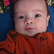 Valentino joined the competition — help win amazing prizes! baby, infant, face, expression, orange_onesie, fox_pattern, blanket, colorful_blanket, pink, blue_background, hand, portrait, child, young_baby, cute, wide_eyes, indoor, lying_down, soft_texture, cozy