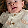 baby, smiling, infant, face, clothing, patterned_shirt, buttons, lying_down, portrait, happy, indoors, closeup, child, cute, skin, person, fabric, texture, background, head