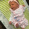 baby, bed, child, cozy, cute, face, foot, hand, headband, indoor, infant, lying_down, newborn, patterned_blanket, person, pink_clothing, sleepwear, smiling, soft_toys, striped_blanket