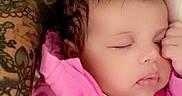 Ariyah joined the competition — help win amazing prizes! baby, infant, sleeping, pink_jacket, blanket, bed, portrait, close_up, face, closed_eyes, curly_hair, peaceful, indoors, cuddling, adult_arm, tattoo, cozy, nap, bedding, photography