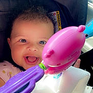 Ariyah joined the competition — help win amazing prizes! baby, child, infant, smiling, happy, portrait, car_seat, car, toy, rattle, pink_toy, purple_toy, blanket, sitting, face, eyes, open_mouth, sunlight, indoor, close_up