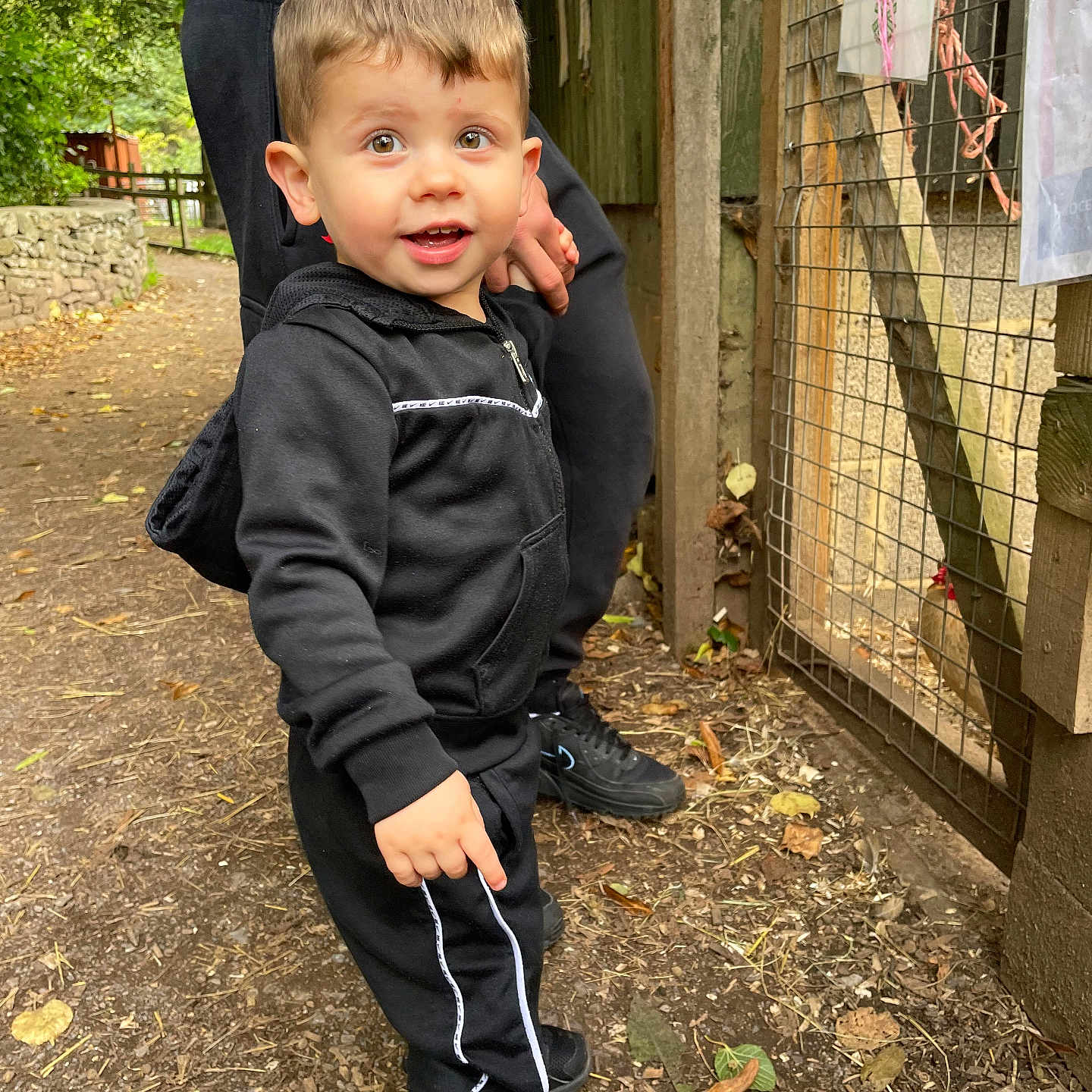Ajay joined the competition — help win amazing prizes! adult, black_tracksuit, child, curious, daylight, dirt, fence, hand, leaves, nature, outdoor, path, person, playful, short_hair, smile, sneakers, toddler, trees, wooden_fence