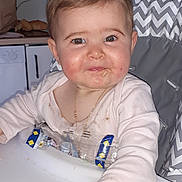 Cloé a rejoint le concours — aidez-le/la à gagner de superbes lots ! baby, high_chair, food, messy, smile, face, hand, kitchen, snack_wrapper, clothing, bracelet, infant, cute, person, indoor, table, cheeky, child, expression, seat