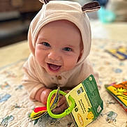 Oscar joined the competition — help win amazing prizes! baby, child, smiling, hood, ears, toy, book, quilt, pattern, colorful, indoor, happy, cute, infant, playful, hands, face, bright, young, cozy