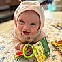 baby, child, smiling, hood, ears, toy, book, quilt, pattern, colorful, indoor, happy, cute, infant, playful, hands, face, bright, young, cozy