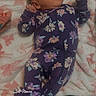 baby, infant, onesie, purple, floral_pattern, blanket, lying_down, curious, face, head, hands, feet, sleepwear, indoor, soft_texture, cozy, infant_clothing, newborn, portrait, timestamp