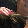 Sabrina joined the competition — help win amazing prizes! person, cat, black_cat, glasses, pink_clothing, heart_pattern, couch, cushion, indoor, relaxing, sleeping_cat, closeup, resting, comfort, casual, home, portrait, face, cozy, pet
