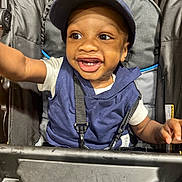 Vincent joined the competition — help win amazing prizes! toddler, child, smiling, cap, navy_blue, vest, stroller, harness, happy, reaching, face, eyes, teeth, clothing, person, baby, seat, infant, cute, joyful