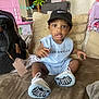 Vincent joined the competition — help win amazing prizes! toddler, child, couch, sneakers, cap, clothing, indoor, toy, backpack, person, face, sitting, home, shoes, furniture, cushion, black_cap, blue_outfit, curious, new_shoes