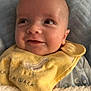 baby, smiling, face, yellow_bib, blanket, infant, clothing, happy, portrait, cute, child, cozy, soft_texture, indoor, closeup, expression, head, skin, sleepwear, newborn