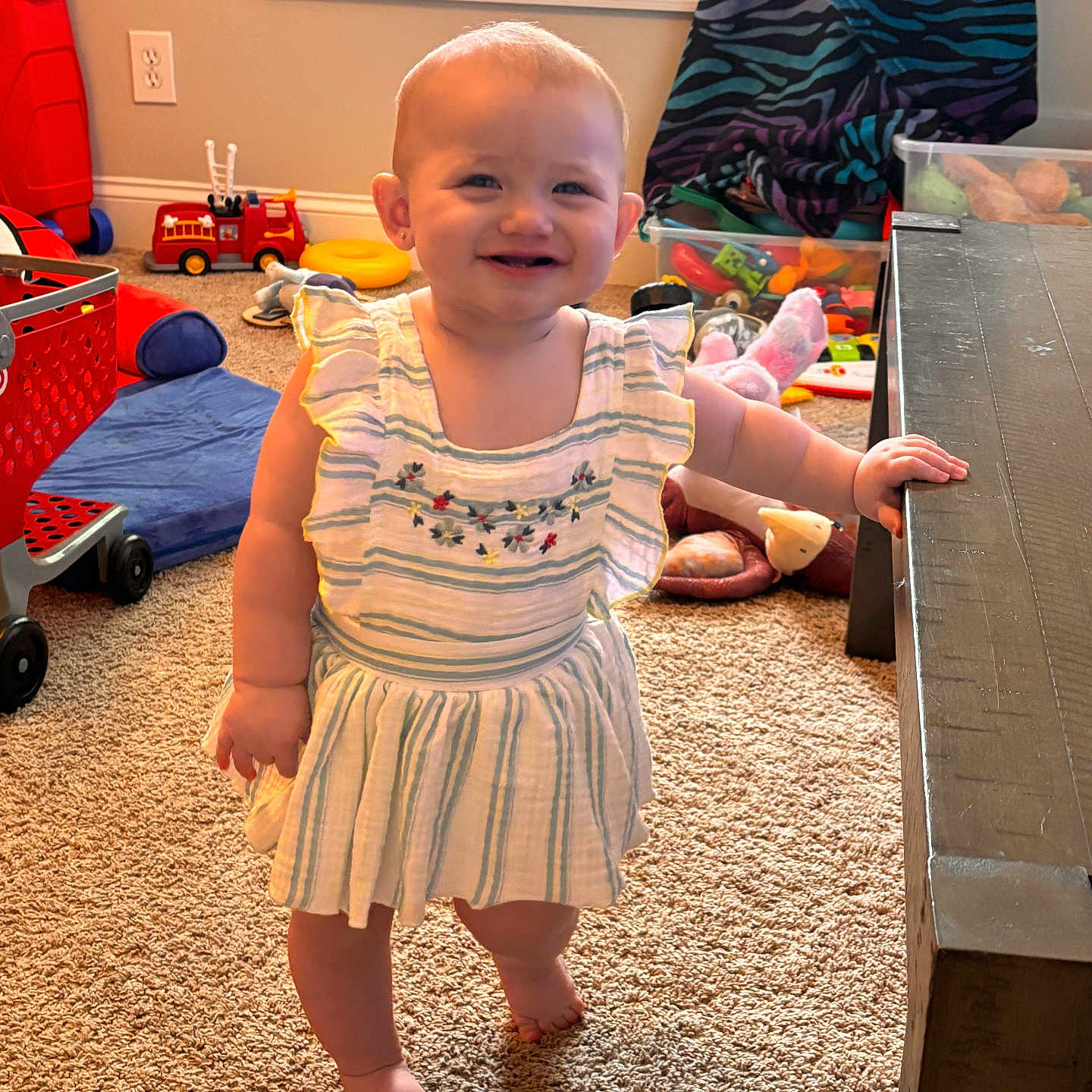 Avery joined the competition — help win amazing prizes! barefoot, carpet, child, colorful, curtain, dress, embroidery, floor, furniture, happy, indoors, person, playroom, smile, standing, striped, table, toddler, toys, window