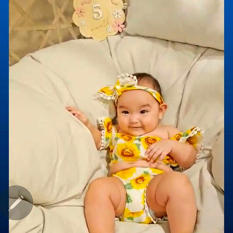 Nya Salyn Cook is registered to the contest to win money with this photo: baby, child, cozy, cushion, happy, headband, indoors, infant, legs, milestone_sign, number_5, outfit, pillow, playback_bar, portrait, sandals, seat, smile, sunflower_print, video_screenshot