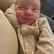 Eliza is registered to the contest to win money with this photo: baby, infant, face, expression, onesie, clothing, stars_pattern, sleepy, cute, portrait, closeup, skin, person, newborn, soft_light, indoors, snuggle, cozy, head, small