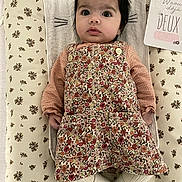 Rose participe au concours pour gagner de l'argent avec cette photo : baby, infant, child, floral_pattern, blanket, dress, sweater, lying_down, face, curious, indoor, card, text, person, cute, young_child, head, clothing, pattern, soft_lighting