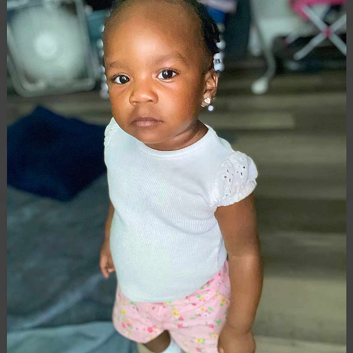 Damira joined the competition — help win amazing prizes! carpet, child, earrings, ears, expression, face, floor, furniture, hair, home, indoor, looking_at_camera, person, pink_shorts, portrait, skin, socks, standing, toddler, white_top