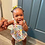 Damira joined the competition — help win amazing prizes! toddler, child, baby, indoor, standing, hand_holding, colorful_clothing, floral_pattern, socks, door, wooden_floor, skin, hair_bows, cute, portrait, smiling, person, young_child, balance, home
