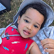 Maé participe au concours pour gagner de l'argent avec cette photo : child, toddler, boy, face, hat, red_clothing, cartoon_print, outdoor, grass, blanket, portrait, smiling, cute, baby, headwear, casual_clothing, daylight, skin, hand, expression