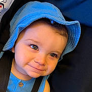 Kian is registered to the contest to win money with this photo: toddler, child, baby, blue_hat, blue_clothing, smile, face, eyes, cute, portrait, headwear, infant, closeup, young_child, person, seatbelt, indoor, skin, expression, baby_fashion